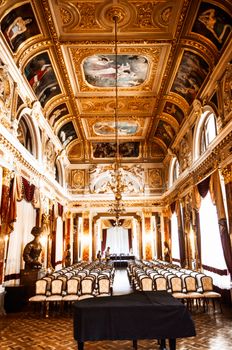 Row of chairs and piano in spacious Renaissance styled Mirror Hall of Lviv Theatre of Opera and Ballet with richly decorated golden walls and ceiling