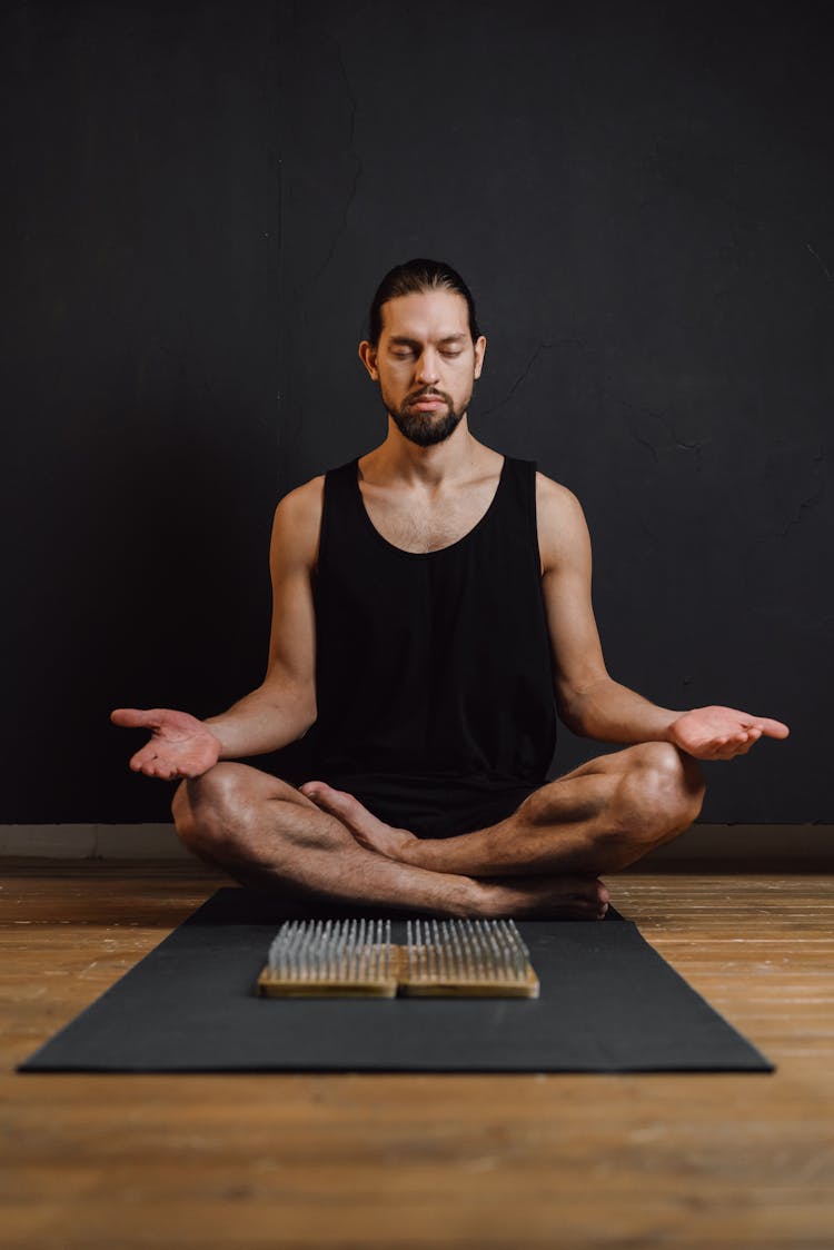 Man In Black Sleeveless Shirt Sitting On Yoga Mat