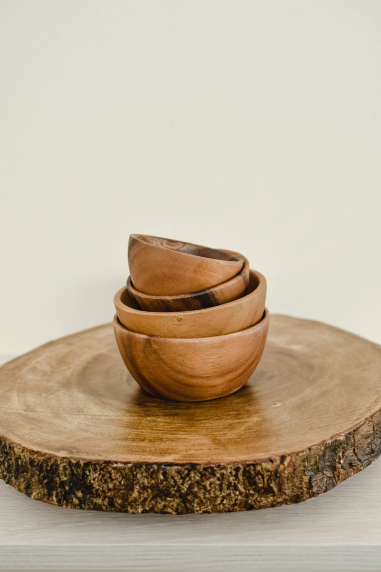 Three stacked wooden bowls on a slice of timber — photo by Eva Bronzini on Pexels