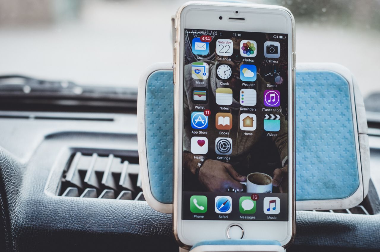 close up of a smartphone mounted on a car dashboard showing home scree