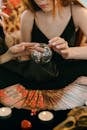 Crop unrecognizable female fortune tellers reading future with magical crystal ball and tarot cards during spiritual session