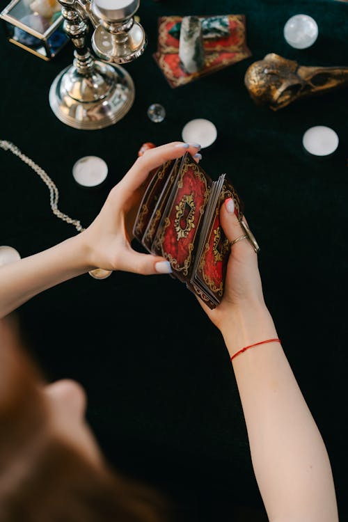 Free Anonymous female fortune teller shuffling tarot cards at table Stock Photo