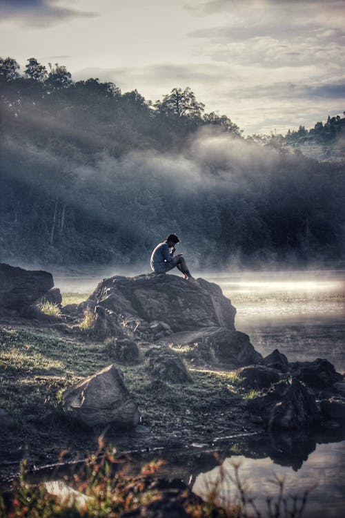 Free Man in Gray Shit Sitting on Rock Boulder Stock Photo