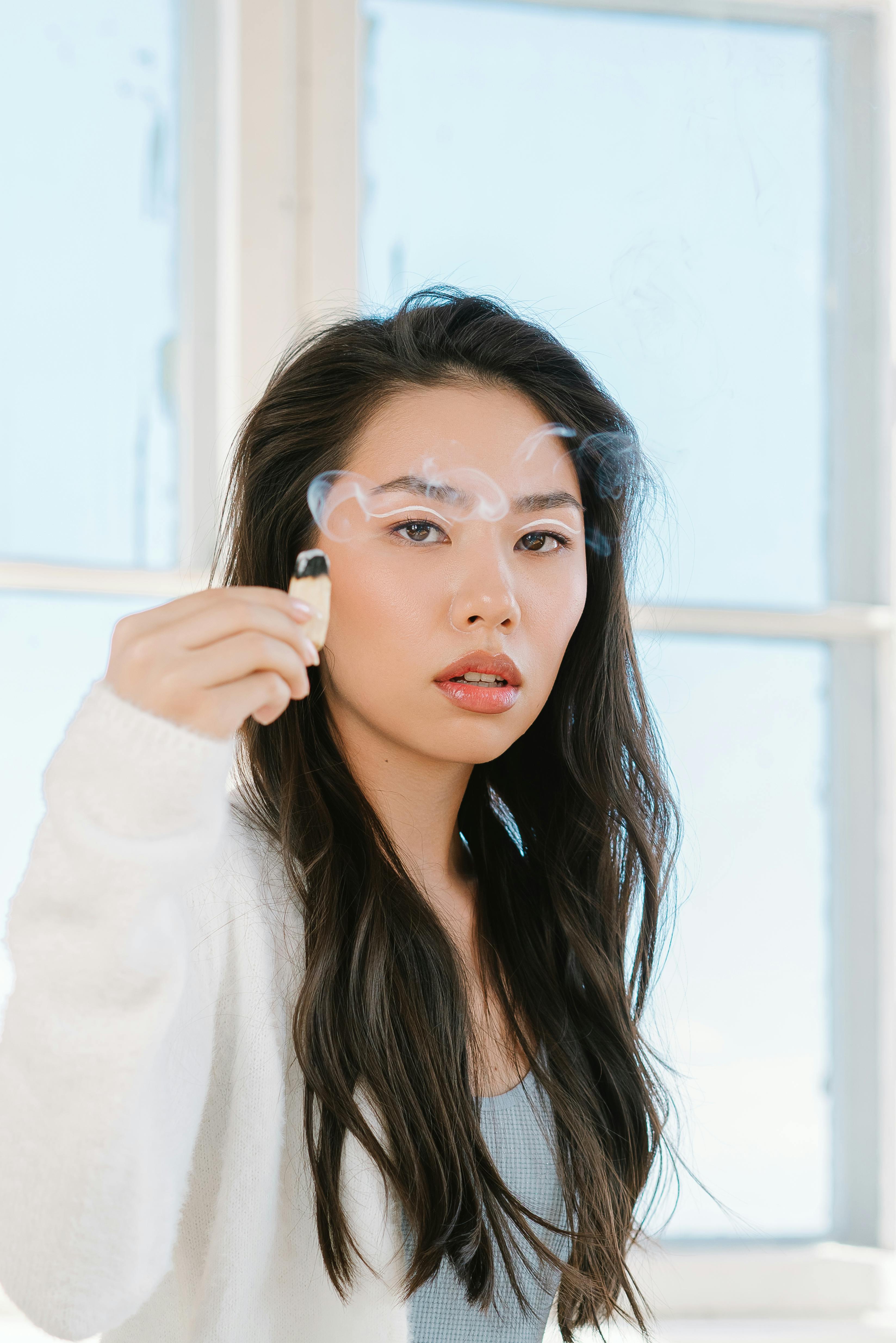 一位时尚女士在室内捧着燃烧的帕洛桑托，营造出一种宁静的氛围