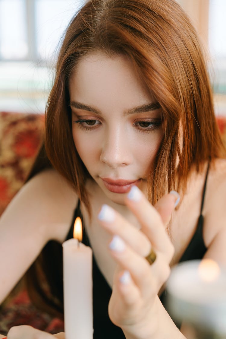 A Woman In Black Tank Top Looking At The Candle