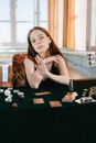 Woman in White Sleeveless Dress Sitting on Table With Chess Pieces and Condiment Shakers