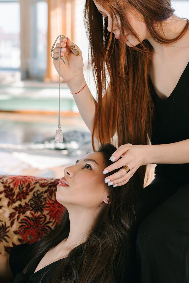 A Woman In Black Shirt Looking At The Pendulum Holding By The Woman In Black Clothes