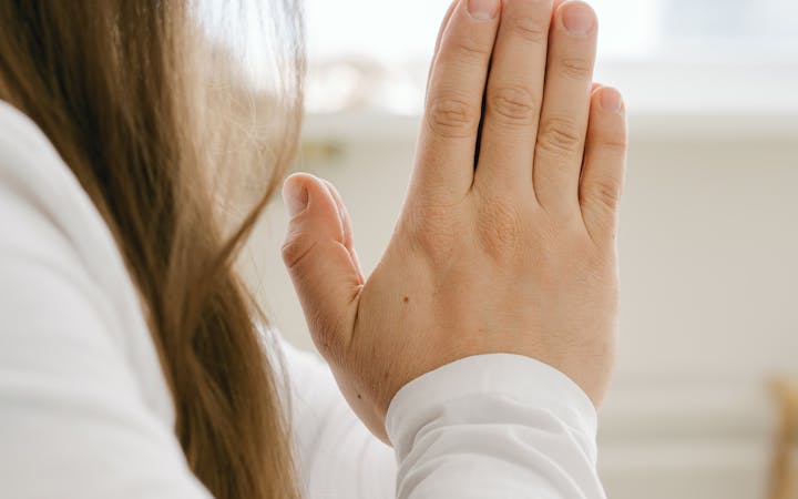 A serene moment of meditation indoors with hands in prayer pose and long hair visible.