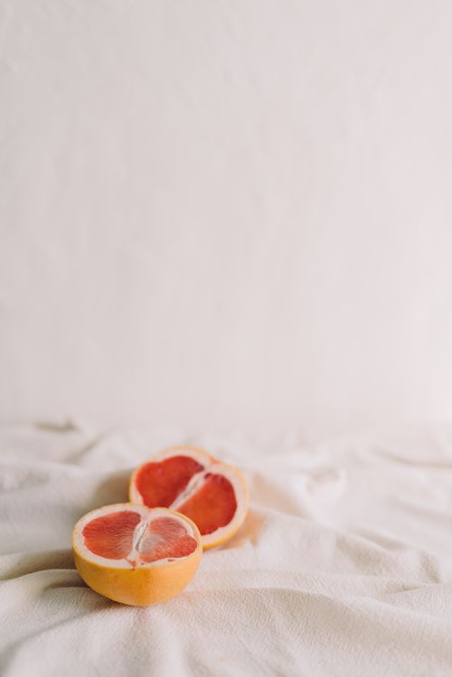 Free A simple and elegant still life featuring a sliced grapefruit on a fabric background, perfect for design aesthetics. Stock Photo