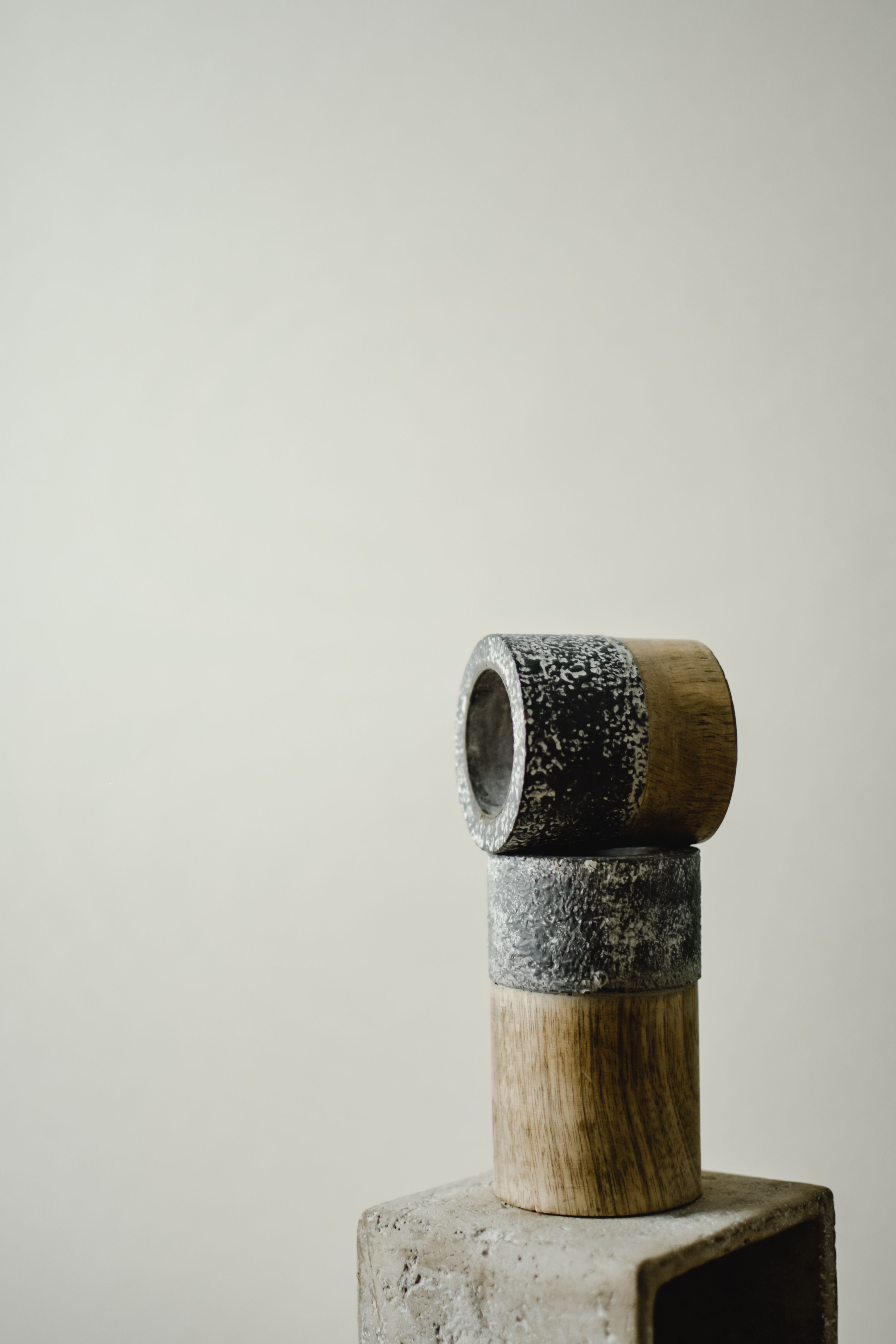 Abstract minimalist sculpture made of stone and wood with a neutral background, emphasizing calm and balance.