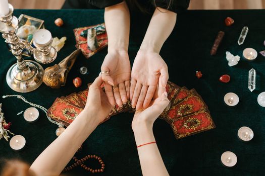 A mystical scene featuring palm reading, tarot cards, candles, and crystals on a dark cloth.