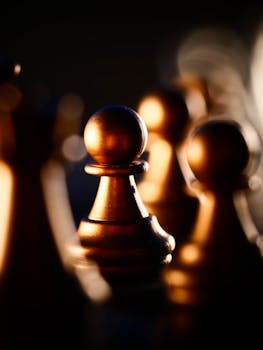 Close-up of golden chess pieces with dramatic lighting and shallow depth of field.