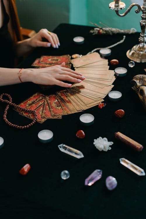 Free High angle of crop anonymous female fortune teller with tarot cards and stones with candles during divination process Stock Photo