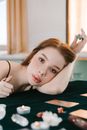 Woman leaning on hand sitting at table with divination cards