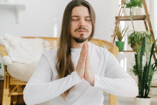 Free Peaceful male meditating with namaste gesture in apartment Stock Photo