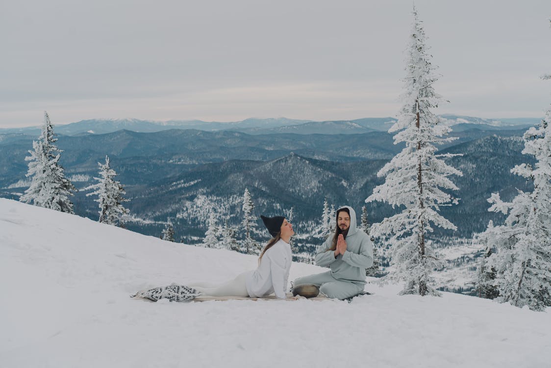 Free Peaceful couple meditating on snowy ground in highland Stock Photo