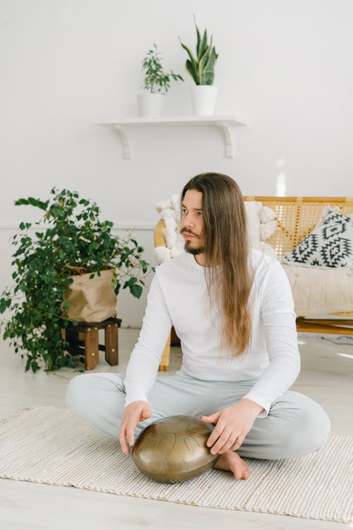 Free Barefoot male with long hair playing on hapi drum Stock Photo
