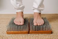 Crop unrecognizable male standing on wooden board with sharp metal nails for recovery and energy during spiritual session