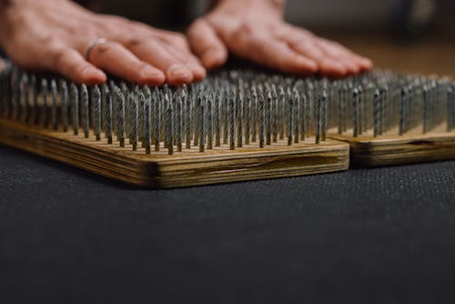 Crop man placing arms on sharp nails