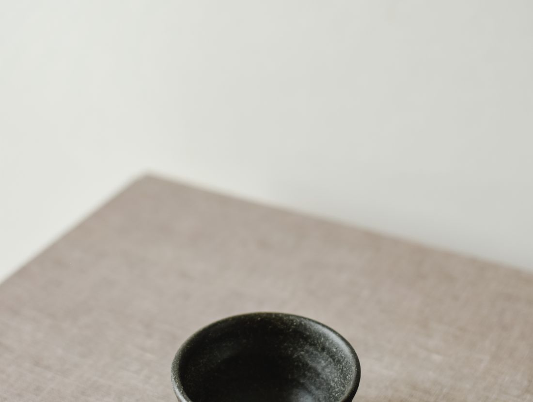 A minimalist ceramic bowl displayed on a textured linen surface, reflecting Japandi style.