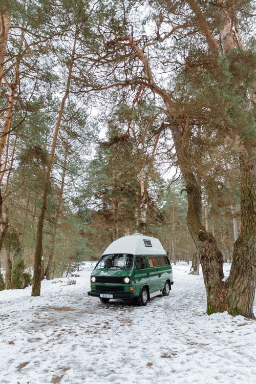 Free Green vintage campervan parked in a serene snowy forest during winter. Stock Photo