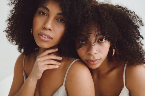 Free Close-up portrait of two women with natural afro curls posing together in a stylish fashion shoot. Stock Photo