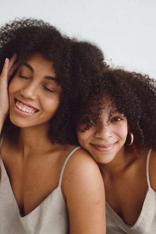 Free Two Young Women in Pajamas Sitting Close to Each Other and Smiling  Stock Photo