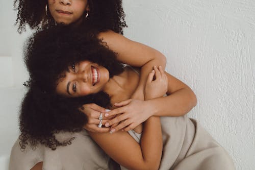 Beautiful Woman with Curly Hair Being Hugged by her Sister
