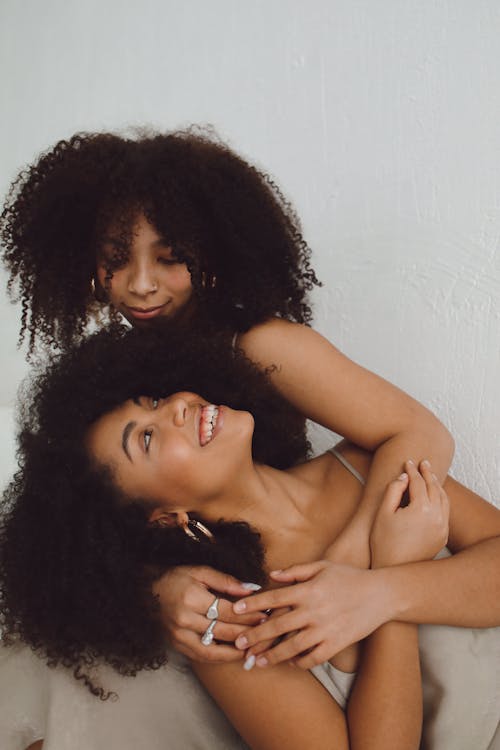 Sisters with Curly Hair Hugging Each Other 