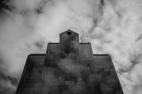 Black and White Photo of a Building Under Cloudy Sky