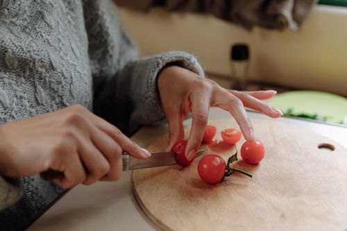Free Hands slicing cherry tomatoes on a cutting board. Perfect for food preparation concepts. Stock Photo