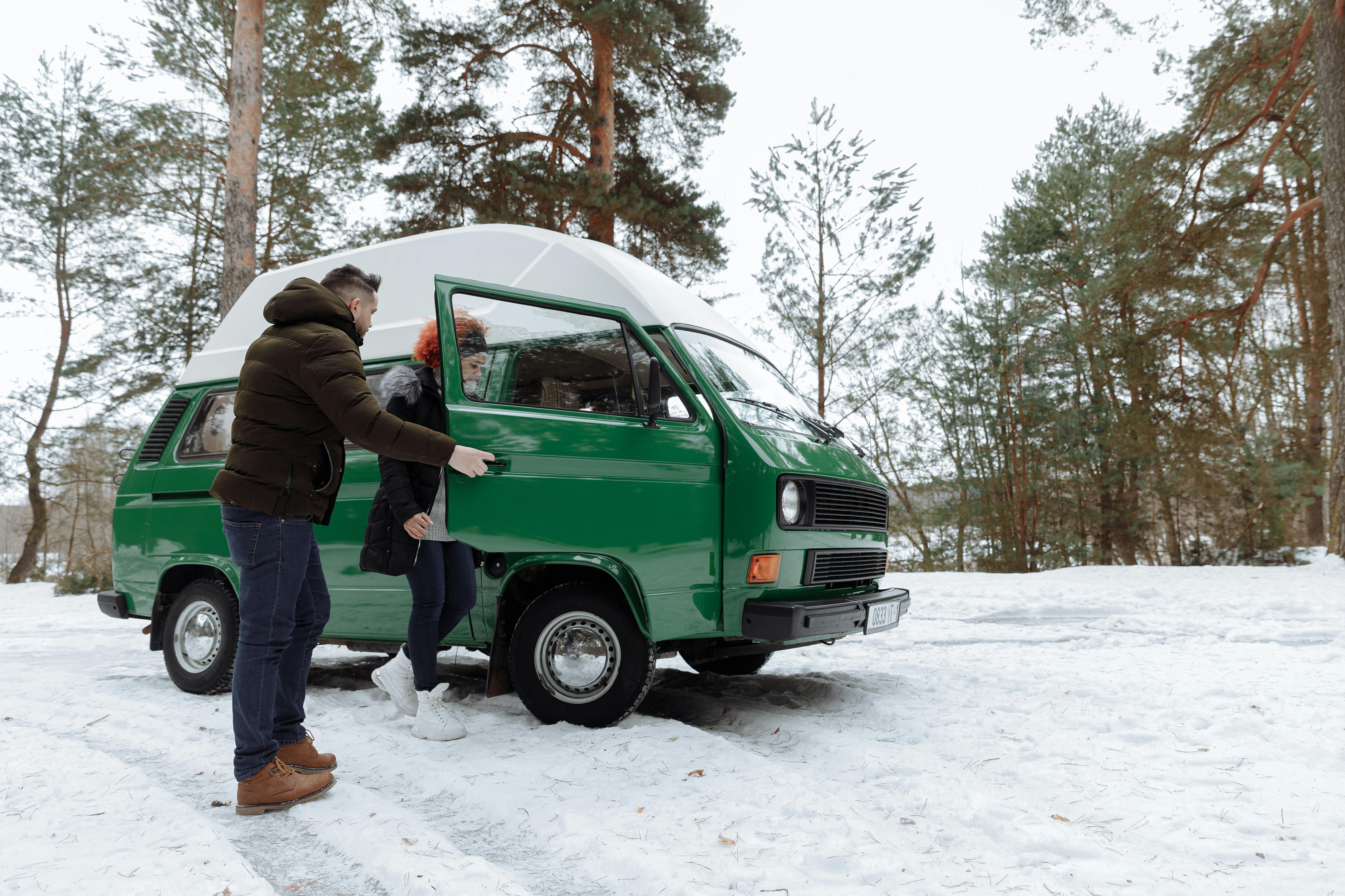 man in green jacket standing beside green car