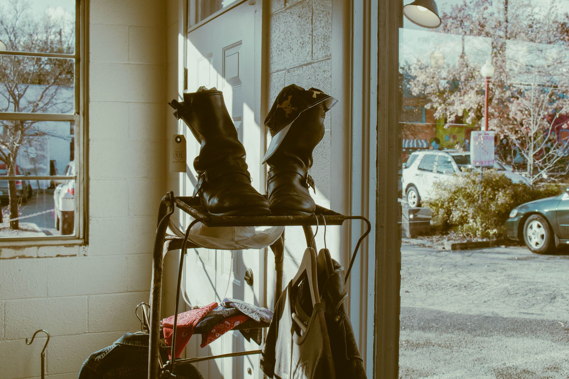 Vintage leather boots on a rack by a sunlit doorway, evoking nostalgia.