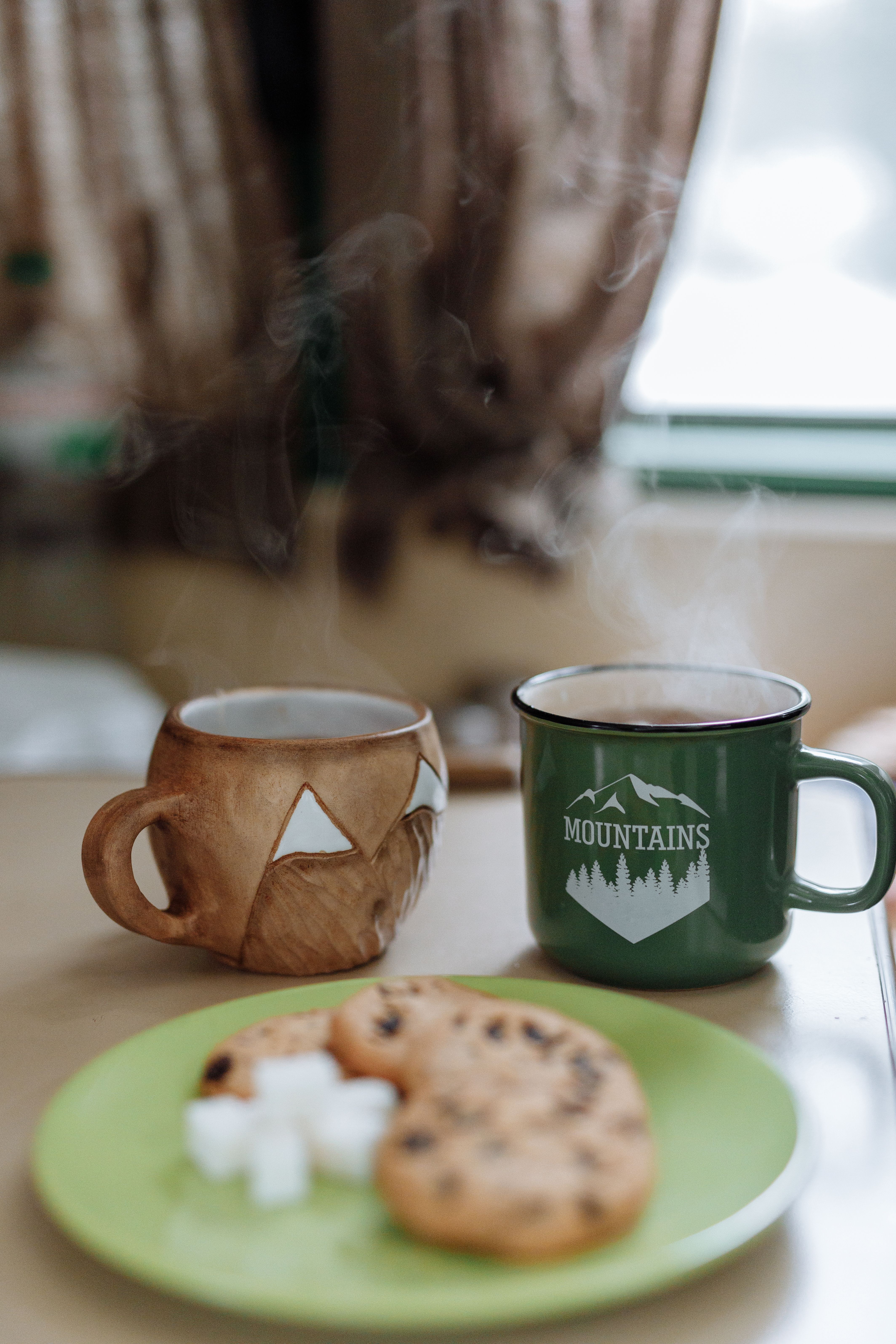 Warm mugs of tea and cookies on a plate, perfect for a cozy winter morning.