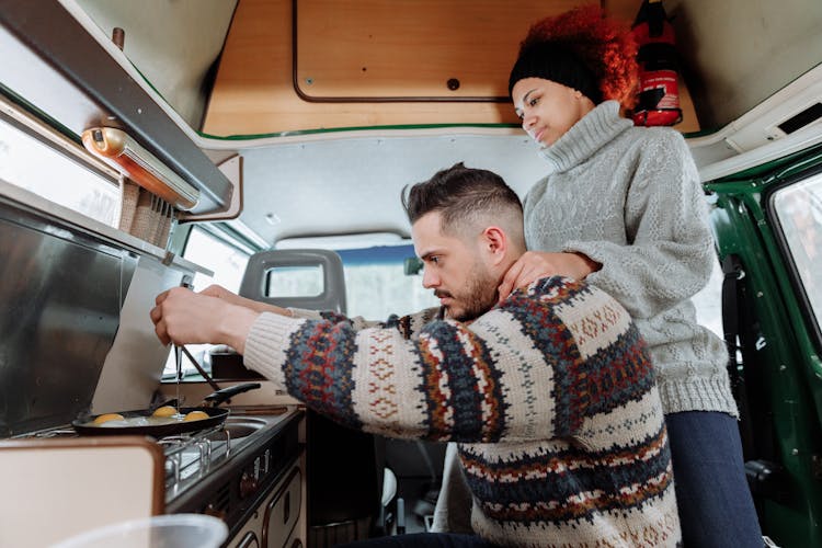 A Man Cooking Eggs Using A Stove In Campervan