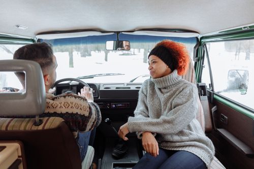 Free Two people enjoying a winter road trip inside a camper van, showcasing warmth and adventure. Stock Photo