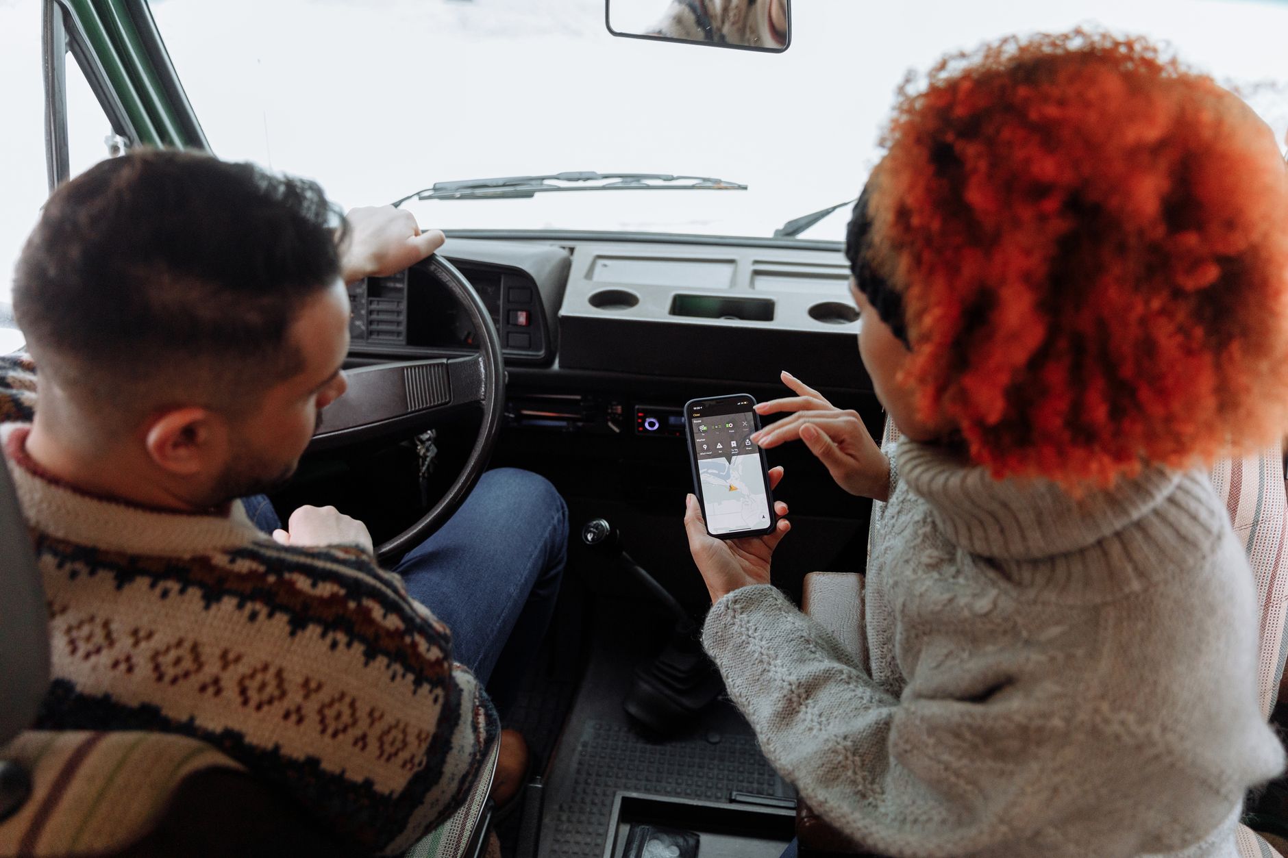 海外自駕離線導航必備:5款App推薦與語音教學 A couple using smartphone navigation while traveling in a van during winter.