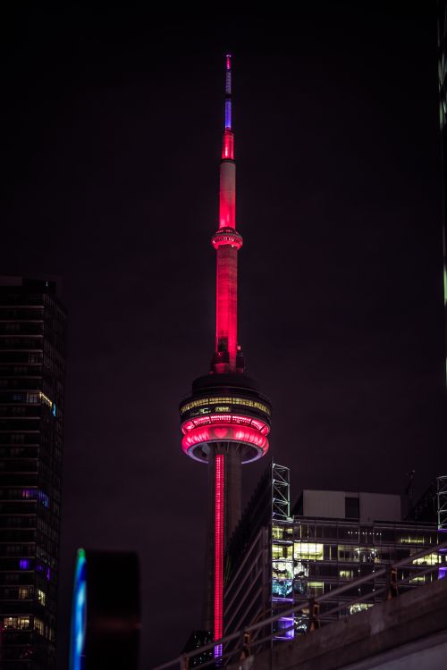 Free A stunning night shot of Toronto's CN Tower illuminated in red with city lights. Stock Photo