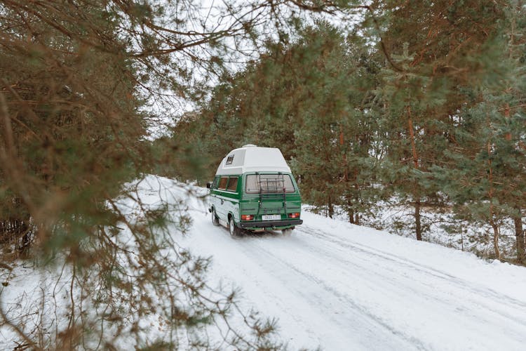 Green Camper Van Driving On Snow Covered Road