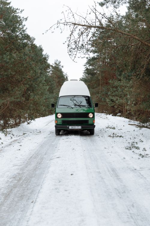 Free A campervan travels on a snowy forest road, showcasing a serene winter landscape ideal for adventure travel. Stock Photo