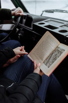 A couple enjoying a book inside a campervan on their road trip adventure.