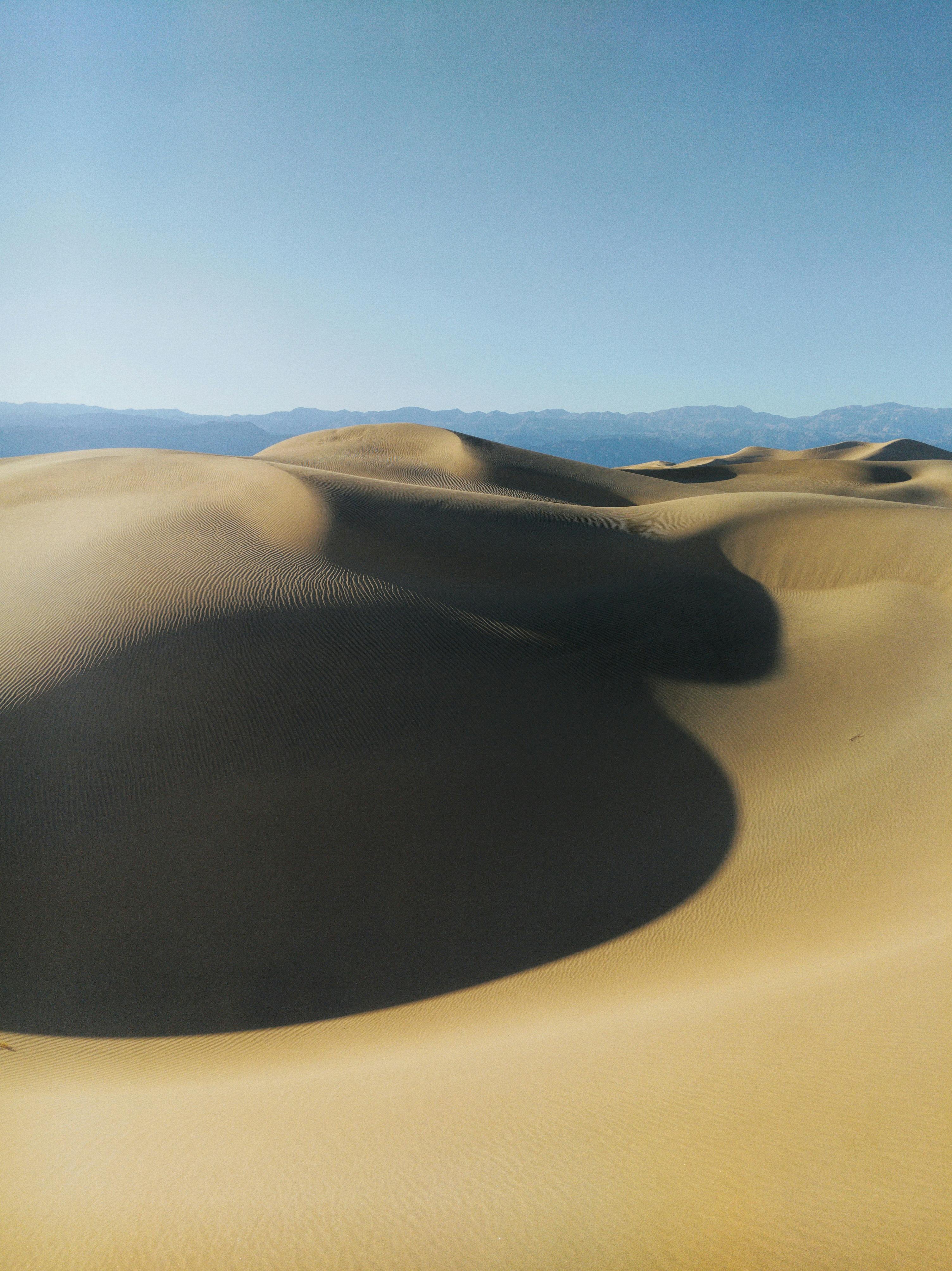 Majestic sand dunes under a clear blue sky in Death Valley National Park, USA.