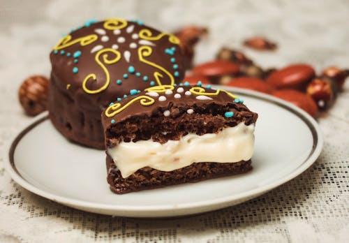 From above of appetizing sweet cakes with cream filling and chocolate glaze placed on plate on table