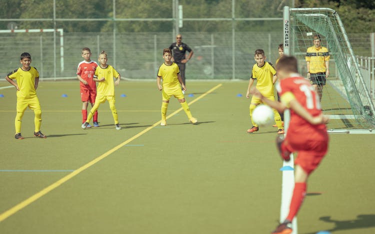 Teenage Football Teams Playing On Outdoor Field