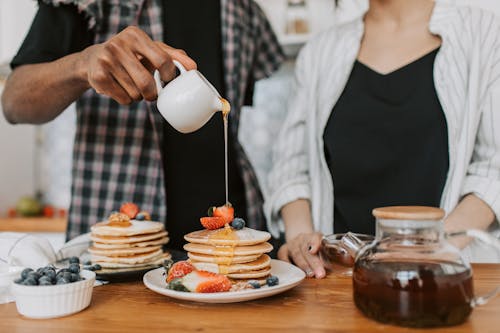 Free 
A Person Pouring Maple Syrup on a Stack of Pancakes Stock Photo