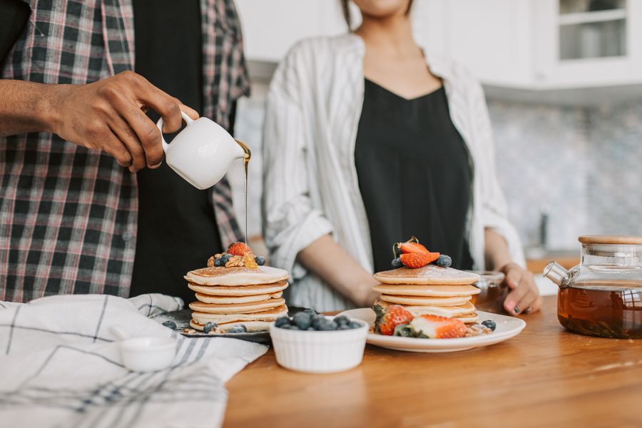 Close-up of pancakes topped with fresh berries and syrup pouring on them