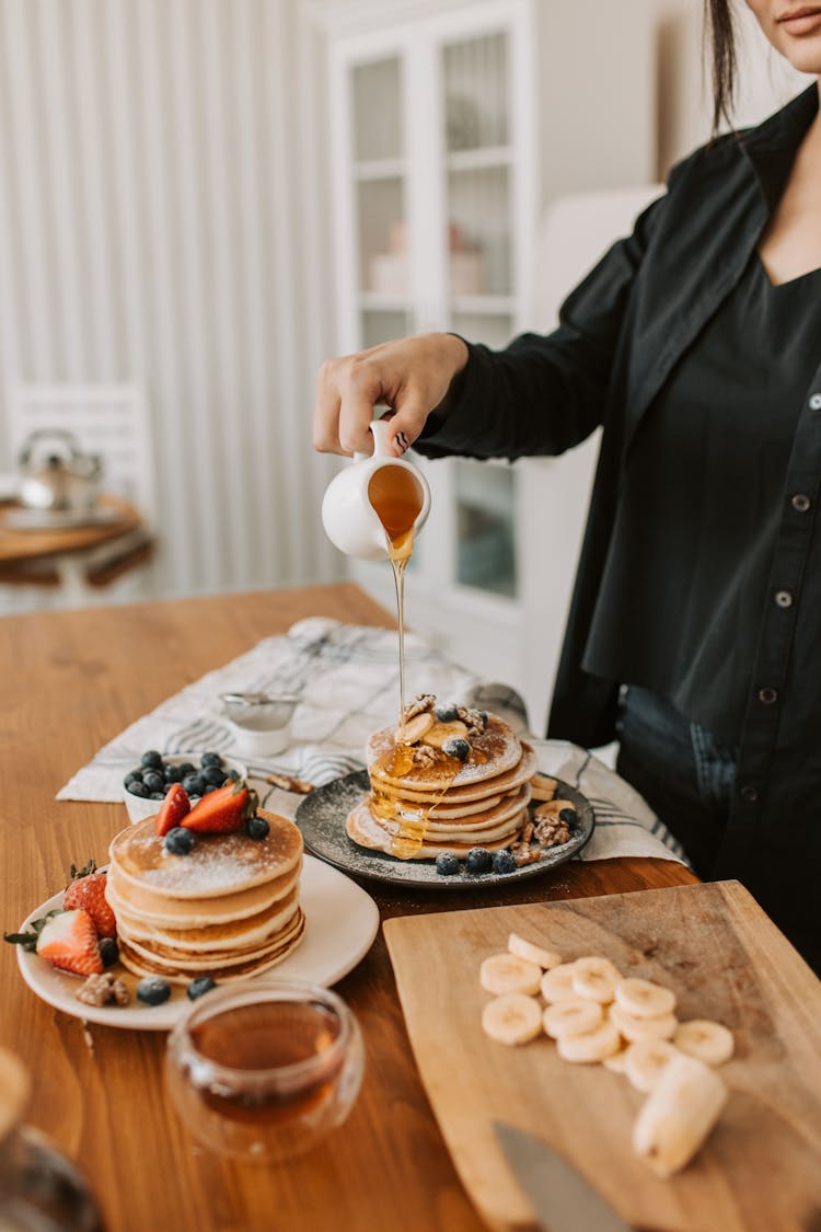 Woman Pouring Syrup On Pancakes