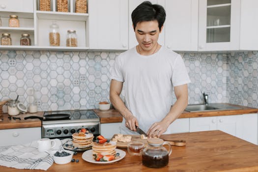 A man slicing bananas for breakfast in a modern home kitchen with fruit pancakes.