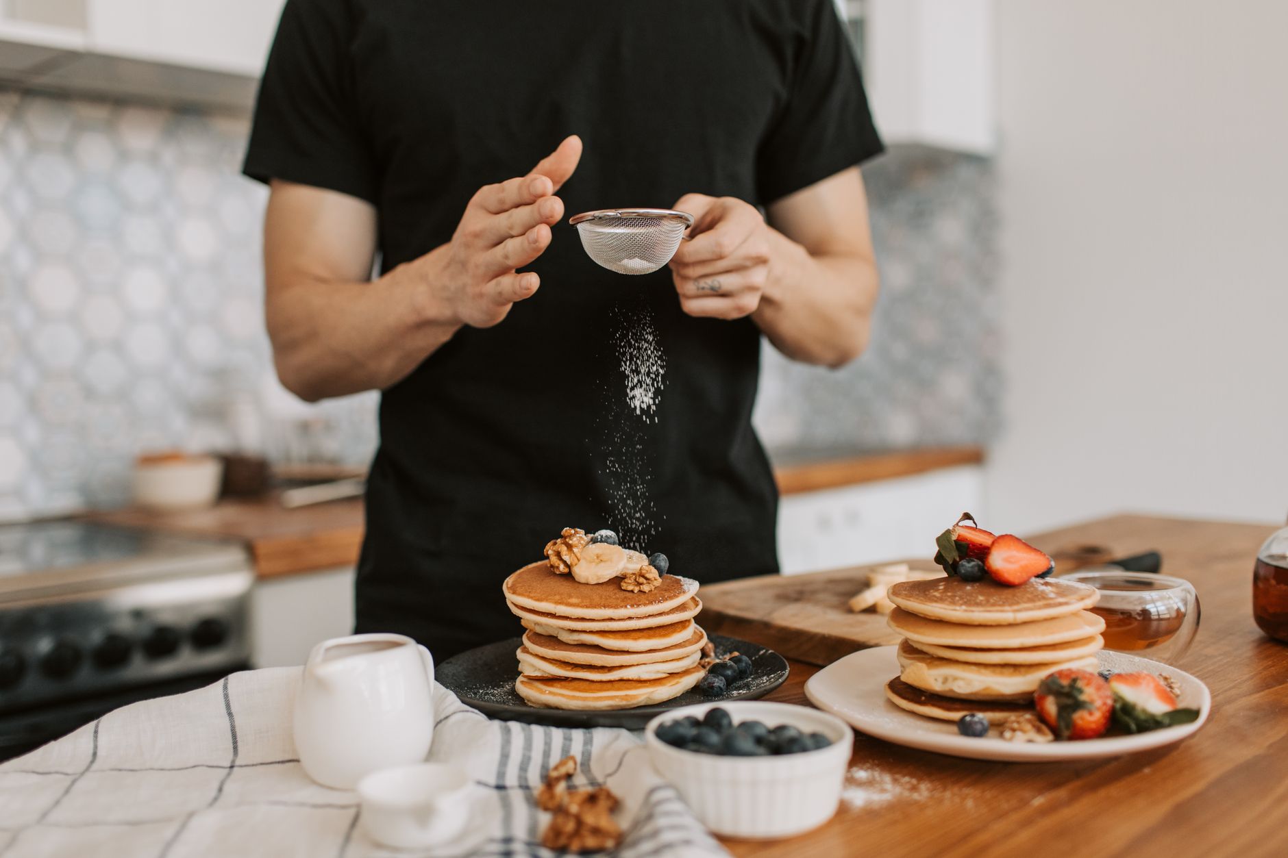 Pancakes being topped with fresh fruit