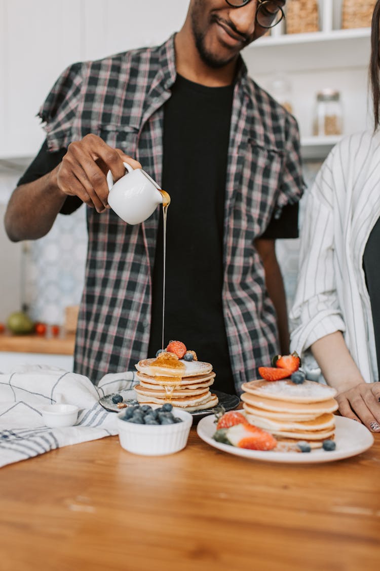 Man Pouring Syrup On Pancakes